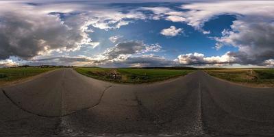 vista de ángulo de 360 grados de panorama hdri esférico completo sin tráfico en carretera asfaltada entre campos por la noche antes de la puesta del sol con cielo nublado. Panorama 360 en proyección equirrectangular, contenido vr ar foto