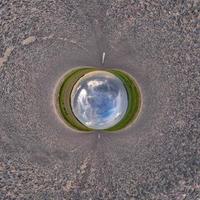 bola de cielo azul en medio de una carretera o campo de asfalto giratorio. inversión de la transformación del pequeño planeta del panorama esférico de 360 grados. vista abstracta esférica. curvatura del espacio. foto