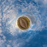 pequeño planeta transformación de panorama esférico 360 grados. vista aérea abstracta esférica en el campo en una agradable velada con impresionantes nubes hermosas. curvatura del espacio. foto