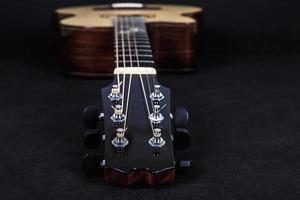 clavijas de afinación en la cabeza de la máquina de madera de cuello de guitarra acústica de seis cuerdas sobre fondo negro foto