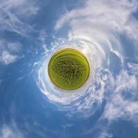 green tiny planet in blue sky with sun and beautiful clouds. Transformation of spherical panorama 360 degrees. Spherical abstract aerial view. Curvature of space. photo