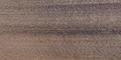 panorama of surface from above of gravel road with car tire tracks photo