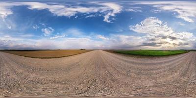 full seamless spherical hdri panorama 360 degrees angle view on no traffic gravel road among fields in evening with cloudy sky in equirectangular projection, ready for VR AR virtual reality content photo