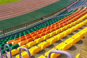 filas multicolores de asientos de plástico en el estadio foto
