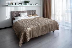 Double bed with pillows in interior of the modern bedroom in loft flat in light color style of expensive apartments photo