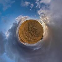 tiny planet in blue sky with sun and beautiful clouds. Transformation of spherical panorama 360 degrees. Spherical abstract aerial view. Curvature of space. photo
