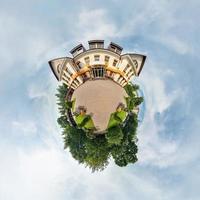 Tiny little planet with trees near beautiful building, white clouds and soft blue sky of amusement park. 360 degrees viewing angel. Planet Earth. photo
