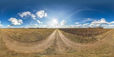 panorama hdri esférico completo sin costuras vista en ángulo de 360 grados en camino de grava sin tráfico entre campos en primavera con cielo nublado en proyección equirectangular, listo para contenido de realidad virtual vr ar foto