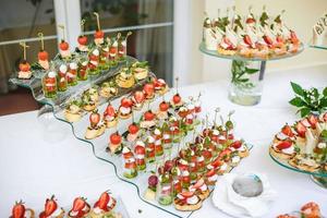 abastecimiento. comida fuera del sitio. mesa de buffet con varios canapés, sándwiches, hamburguesas y bocadillos. foto