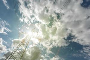 silueta de las torres de pilón eléctrico de alto voltaje en el fondo de hermosas nubes con rayos de sol foto