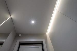 suspended or stretch ceiling with halogen spots lamps and drywall construction in empty room in apartment or house photo