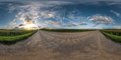 panorama esférico completo sin costuras vista de ángulo de 360 grados en camino de grava entre campos en la puesta de sol de la tarde de verano con nubes impresionantes en proyección equirectangular, skybox vr ar contenido de realidad virtual foto