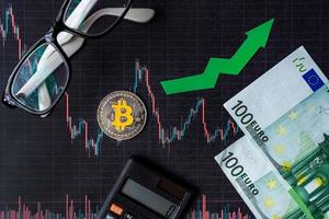 appreciation of virtual money bitcoin. Green arrow and silver Bitcoin on paper forex chart index rating go up exchange market background with euro banknotes. Concept of appreciation of cryptocurrency. photo