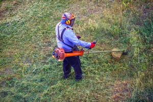 vista superior cortadora de césped hombre trabajador cortando hierba seca con cortadora de césped. foto
