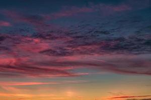 fondo de cielo de puesta de sol rojo violeta azul con nubes de cirrostratos ondulantes rizados y esponjosos por la noche. buen clima ventoso foto