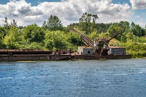 abandoned wreck of old rusty boat half submerged in the river photo