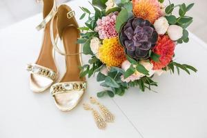 bright wedding bouquet of summer dahlias and roses with women high-heeled shoes photo