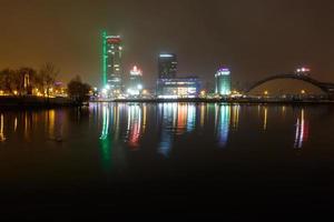 ights of the night city. Light skyscraper reflected in the lake water with fog photo