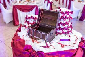 wooden chest on the table with a violet tablecloth and small gifts for guests from the newlyweds photo