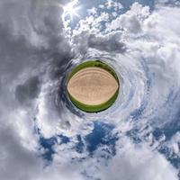 Little planet transformation of spherical panorama 360 degrees. Spherical abstract aerial view in field with awesome beautiful clouds. Curvature of space. photo