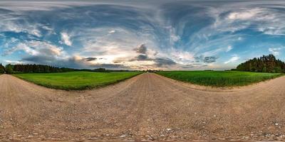 vista de ángulo de 360 grados de panorama hdri esférico completo sin costuras en camino de grava entre campos en la puesta de sol de la tarde de verano con nubes impresionantes en proyección equirectangular, contenido de realidad virtual listo vr ar foto