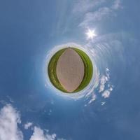 pequeño planeta verde en el cielo azul con sol y hermosas nubes. transformación de panorama esférico 360 grados. vista aérea abstracta esférica. curvatura del espacio. foto