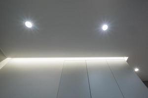 suspended or stretch ceiling with halogen spots lamps and drywall construction in empty room in apartment or house photo