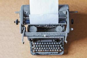 vieja máquina de escribir vintage cubierta de polvo con una hoja de papel blanco foto