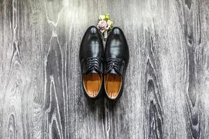 black groom's shoes with boutonniere on the parquet floor photo