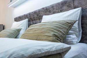 cama doble con almohadas en el interior de la habitación moderna en loft con estilo de color claro de apartamentos caros foto