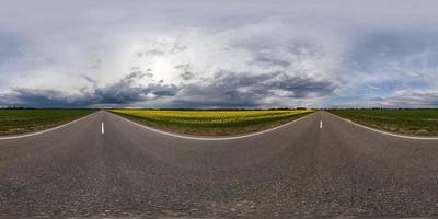 vista de ángulo de 360 grados de panorama hdr esférico completo en carretera asfaltada entre campos por la noche con impresionantes nubes negras antes de la tormenta en proyección equirectangular, vr ar contenido de realidad virtual foto