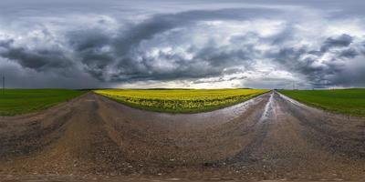 Full spherical seamless hdri panorama 360 degrees angle view on wet no traffic asphalt road near rapeseed canola fields with black sky after storm in equirectangular projection, VR AR content photo