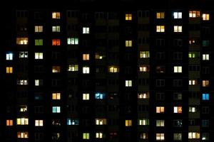 lapso nocturno de luz en las ventanas de un edificio de varios pisos. la vida en una gran ciudad foto