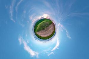 pequeño planeta transformación de panorama esférico 360 grados. vista aérea abstracta esférica en el campo en una agradable velada con impresionantes nubes hermosas. curvatura del espacio. foto