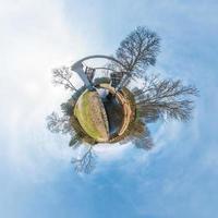Green little tiny planet with trees near gateway lock sluice construction on river, white clouds and soft blue sky of amusement park. 360 viewing angel. Planet Earth. photo