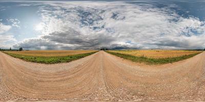 panorama hdri esférico completo sin costuras vista en ángulo de 360 grados en camino de grava entre campos con impresionantes nubes antes de la tormenta en proyección equirectangular, listo para contenido de realidad virtual vr ar foto