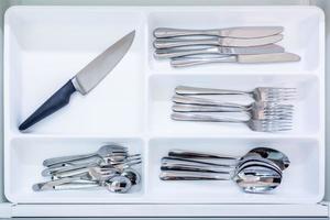 cutlery spoons forks knives and tea spoon on the shelf in the kitchen cupboard photo