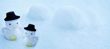 White snowman in a black hat in the snow. photo