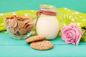 Milk, cookie, oat flakes. Breakfast and pink rose on blue wooden background and lace napkin. Top view and copy space. Mothers day. photo