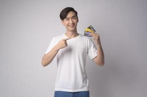 Young asian man holding credit card over white background studio, shopping and finance concept. photo