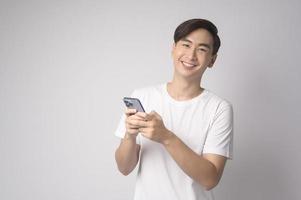 joven asiático usando un teléfono inteligente sobre fondo blanco, concepto de tecnología. foto