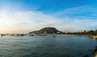 vista aérea de la ciudad de vung tau con hermosa puesta de sol y tantos barcos. vista panorámica costera de vung tau desde arriba, con olas, costa, calles, cocoteros y montaña tao phung en vietnam. foto