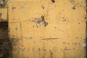 Texture of old yellow concrete wall for background.  Rough texture on yellow wall rough form due to peeling paint layer due to rain. photo