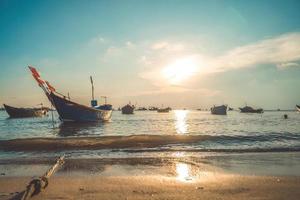Tropical Seascape with a boat on sandy beach at cloudy sunrise or sunset. Beautiful sunset tropical beach with small boat and cinematic sky for travel and vacation in holiday relax time. photo
