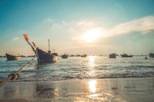 Tropical Seascape with a boat on sandy beach at cloudy sunrise or sunset. Beautiful sunset tropical beach with small boat and cinematic sky for travel and vacation in holiday relax time. photo