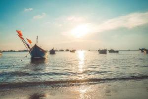 Tropical Seascape with a boat on sandy beach at cloudy sunrise or sunset. Beautiful sunset tropical beach with small boat and cinematic sky for travel and vacation in holiday relax time. photo