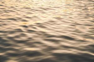 Sunset water reflect ripples at sun light. Abstract golden reflection on water sunset photo