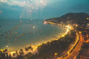 Vung Tau city aerial view with beautiful sunset and so many boats. Panoramic coastal Vung Tau view from above, with waves, coastline, streets, coconut trees and Tao Phung mountain in Vietnam. photo