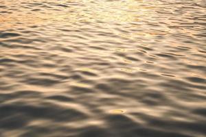 Sunset water reflect ripples at sun light. Abstract golden reflection on water sunset photo