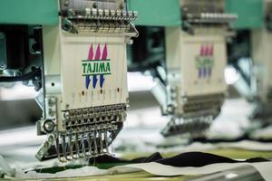 máquina de coser moderna y automática de alta tecnología para el proceso de fabricación de prendas de vestir o textiles en la industria. industria textil digital. bordado computarizado. foto